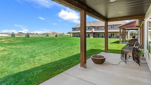 A covered patio area with a concrete floor, a fire pit, and a row of chairs. - Townhome 47, 3 Bed-12 Guests with indoor/Outdoor pools+Rec Center at Waterdance (Garden City)
