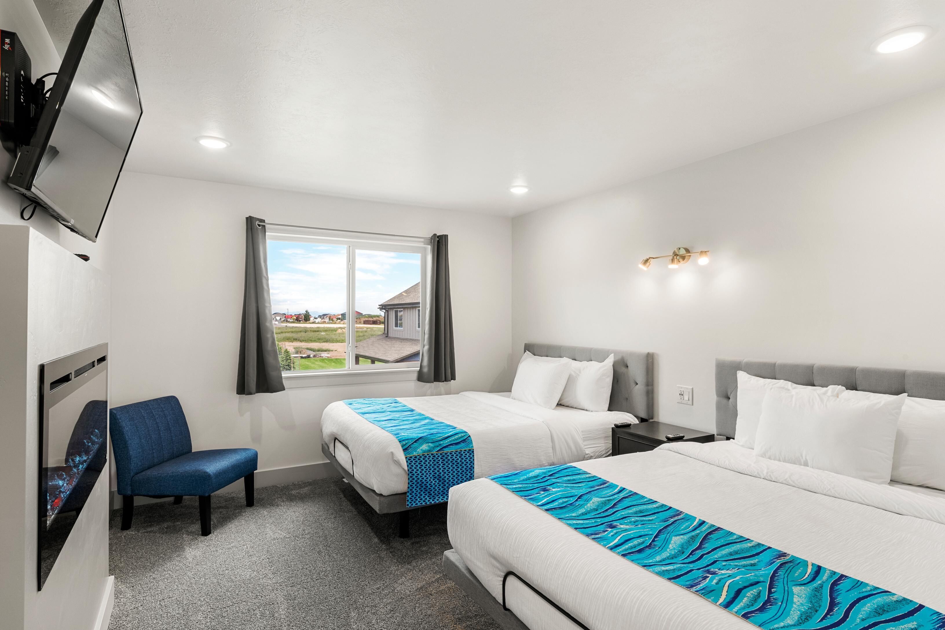 Une chambre d’hôtel avec deux lits, un téléviseur fixé au mur, une fenêtre avec des rideaux et une vue sur l’extérieur.