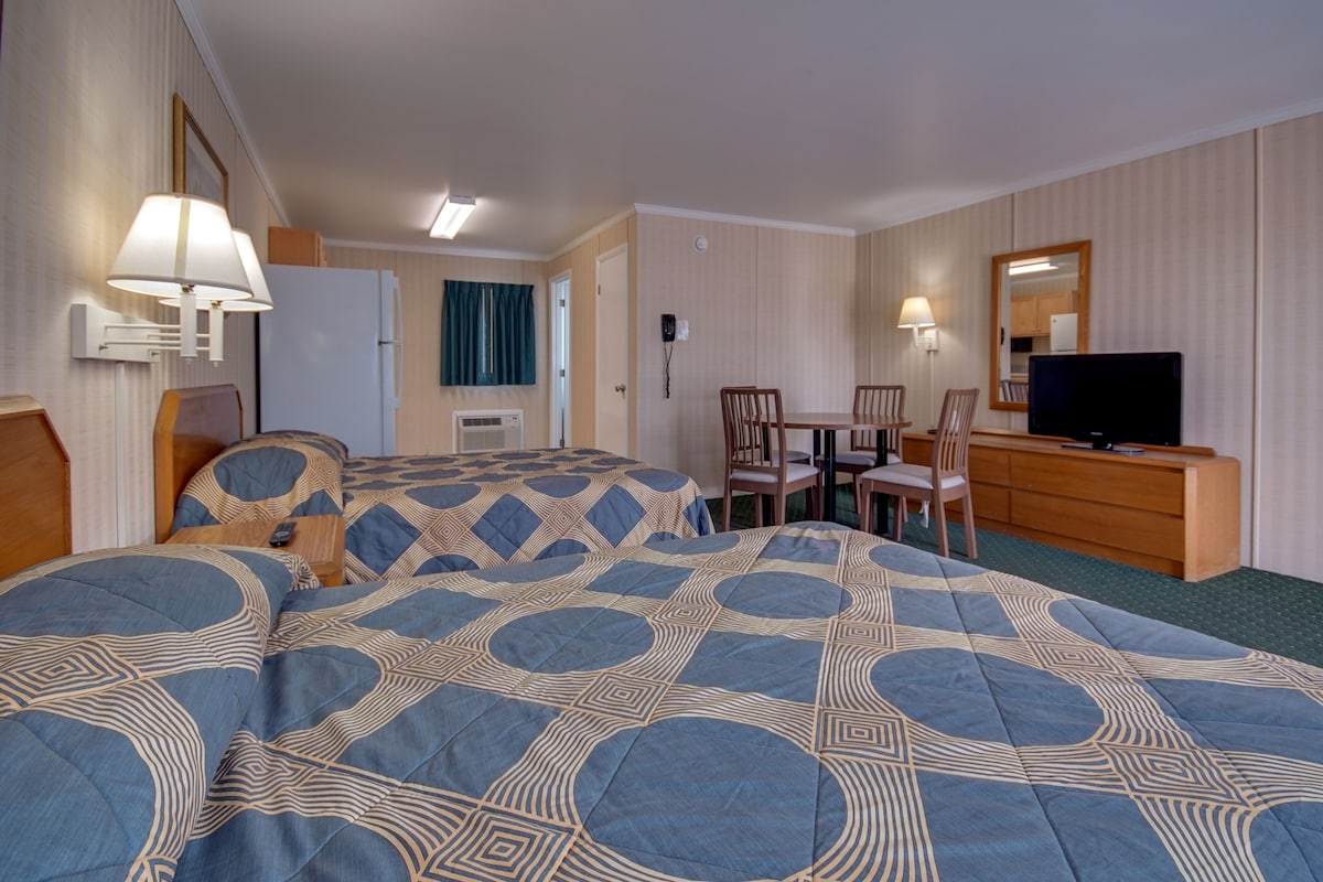 A hotel room with two beds, a TV, a desk, and a chair.
