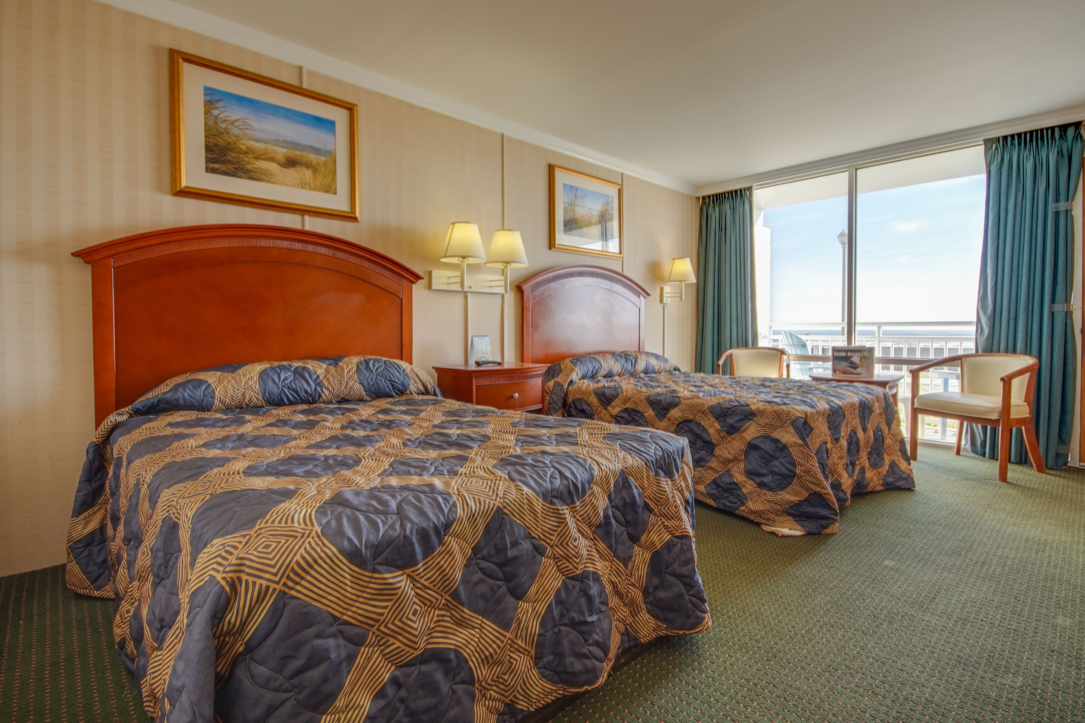Une chambre d’hôtel avec deux lits, un bureau et une chaise. Il y a deux lampes sur le bureau et une fenêtre avec des rideaux.