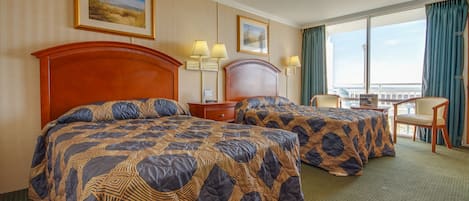 A hotel room with two beds, a desk, and a chair. There are two lamps on the desk and a window with curtains.