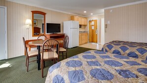 A compact hotel room with a bed, a dining table with chairs, a small kitchenette, and a television. - Sahara Motel (Ocean City)
