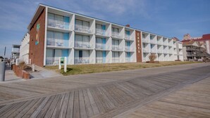 A multi-story hotel with balconies, a wooden boardwalk in front, and a clear sky. - Sahara Motel (Ocean City)