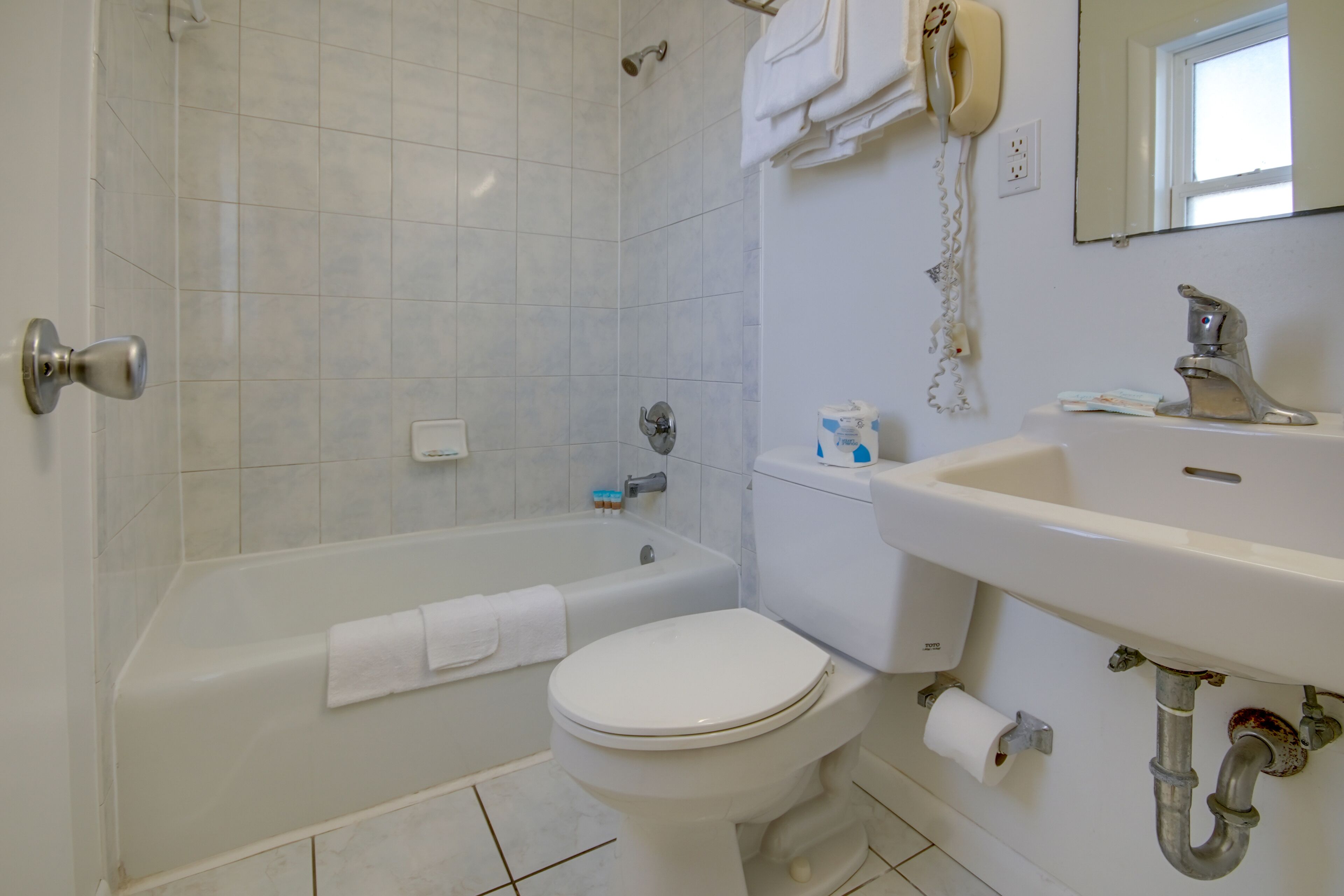Un baño con bañera, inodoro, lavabo y un secador de pelo en la pared.
