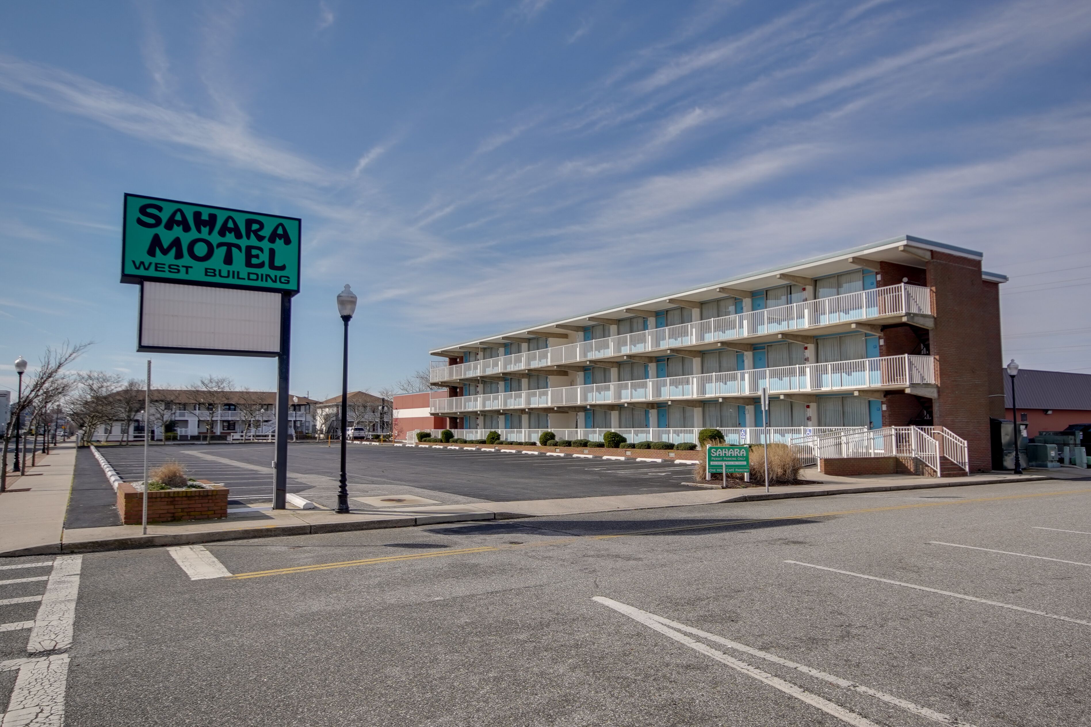 Un motel con un letrero que dice "SAMARA MOTEL WEST BUILDING" y un edificio de varios pisos con balcones.