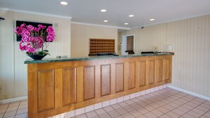 A reception area with a wooden counter, a potted orchid, and a wooden panel wall. - Sahara Motel (Ocean City)