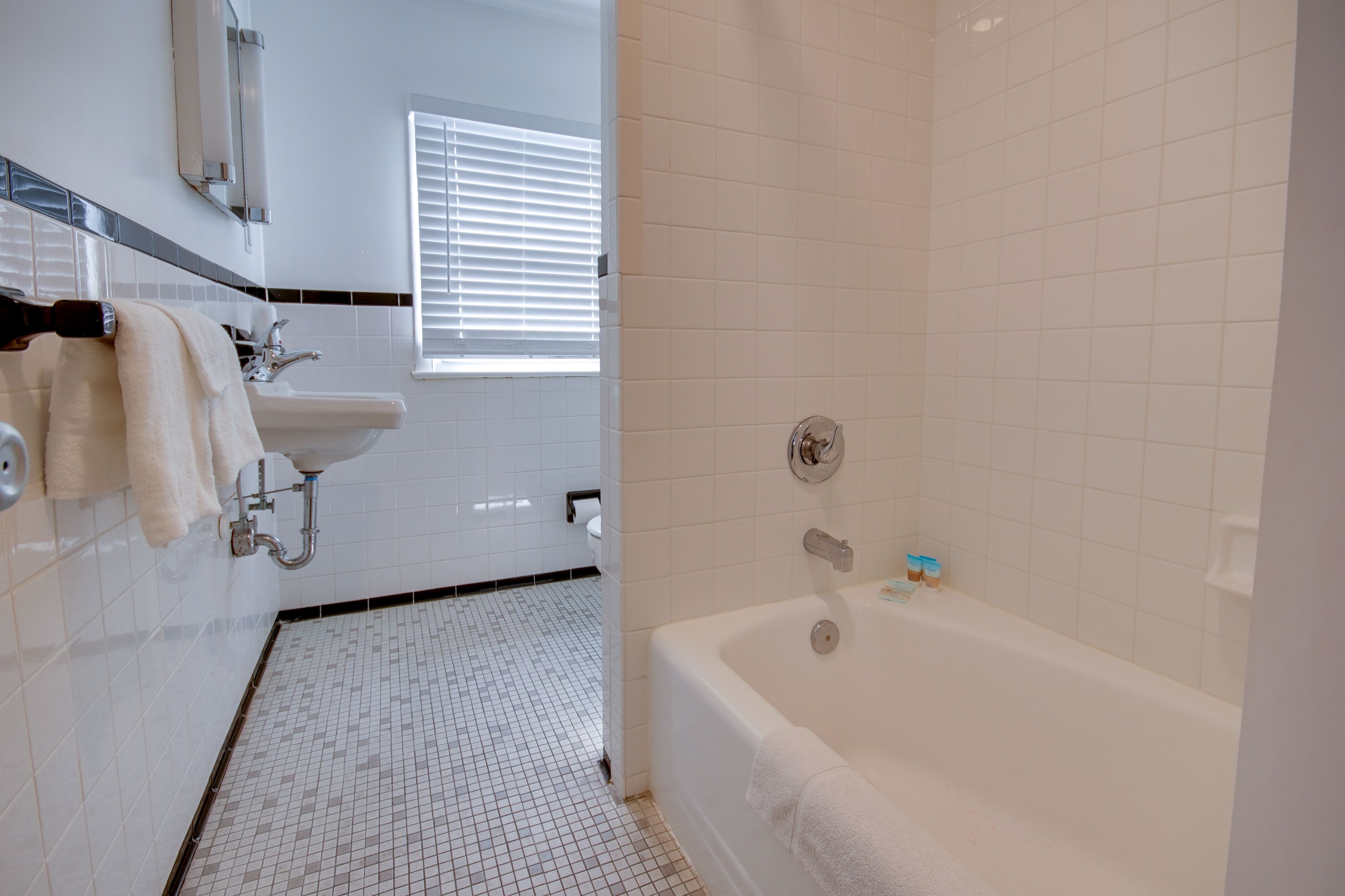 A modern bathroom with a white sink, a bathtub, and a tiled floor.