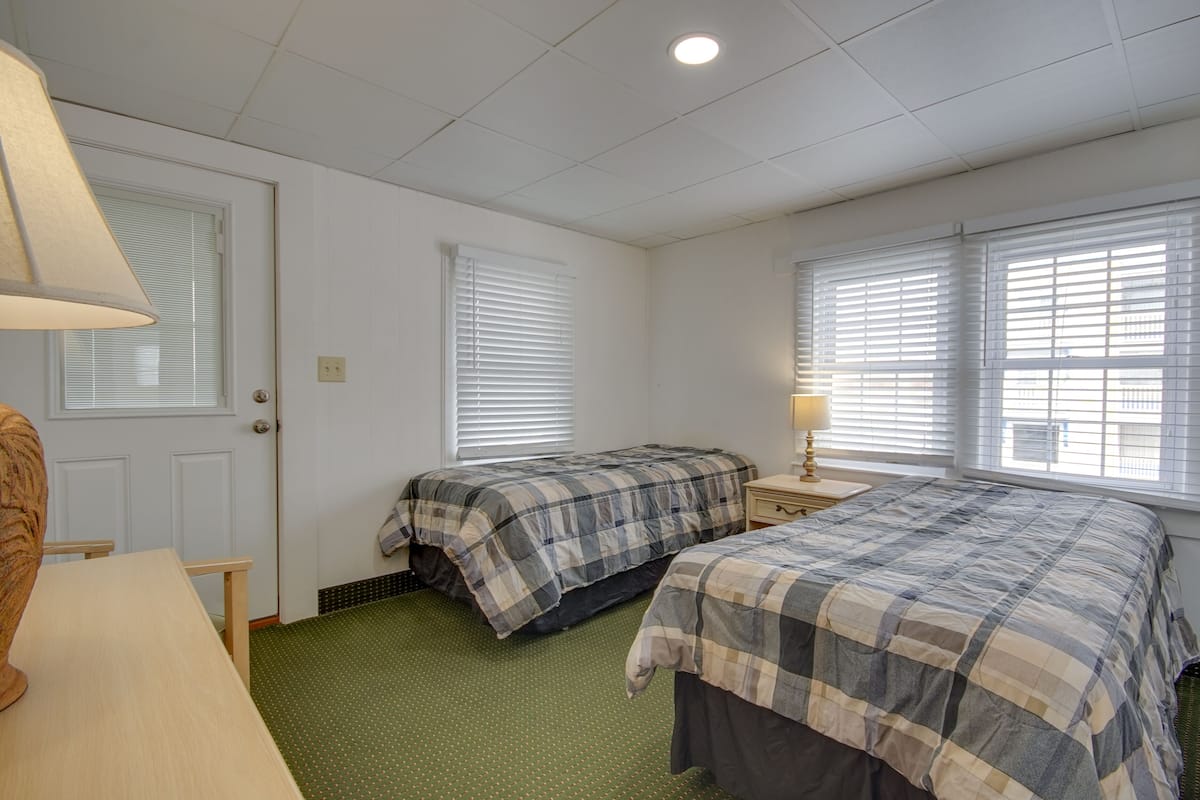 A room with two beds, a desk, and a lamp.
