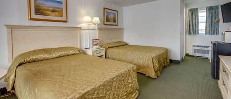 A hotel room with two beds, a TV, and a window with curtains.