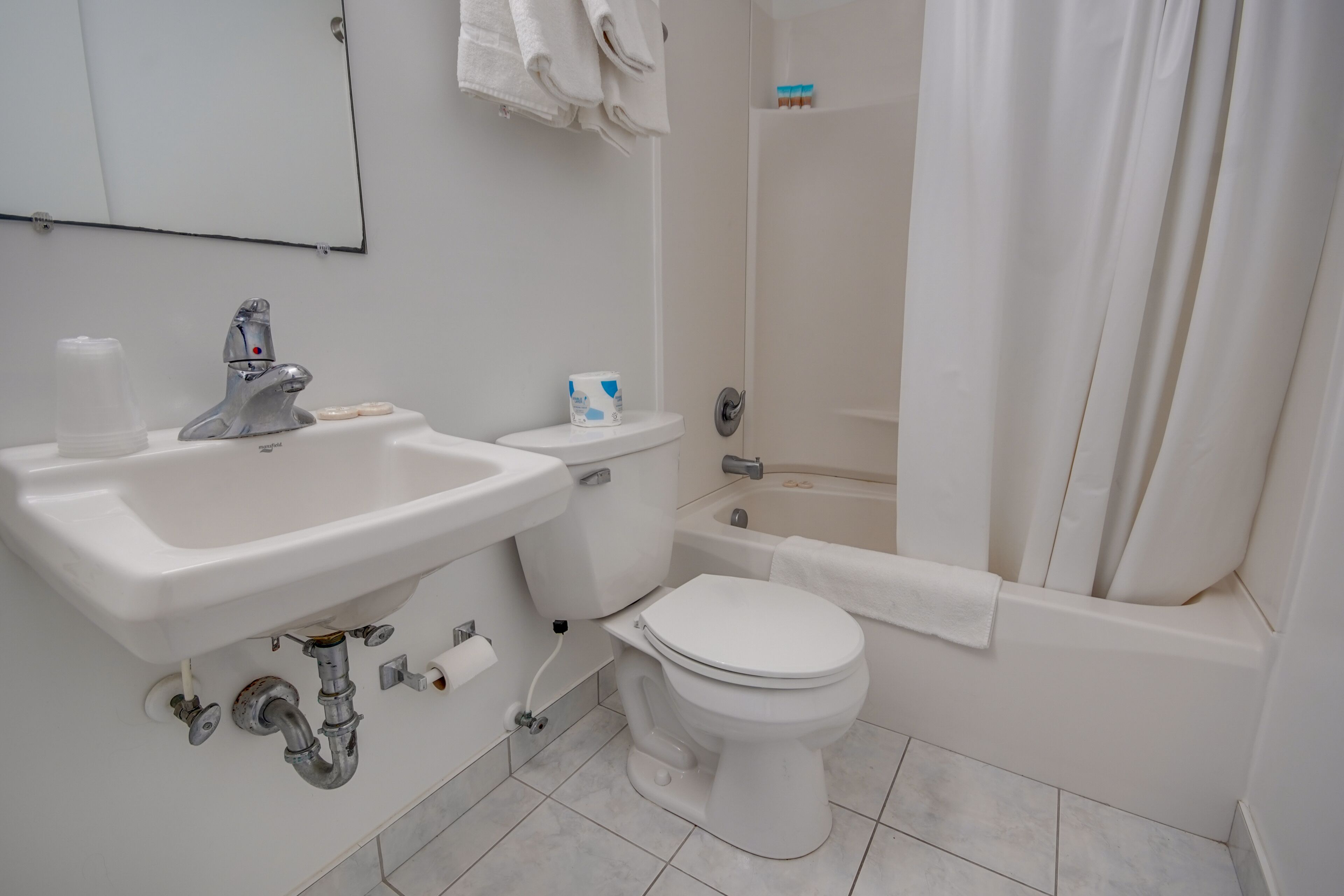 Un baño con lavamanos, inodoro, bañera y cortina de ducha.