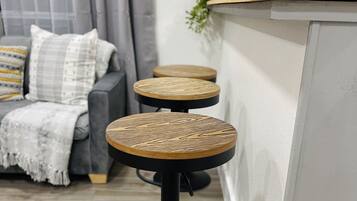 Een moderne keuken met een houten aanrecht en twee krukken met gevlochten zittingen.