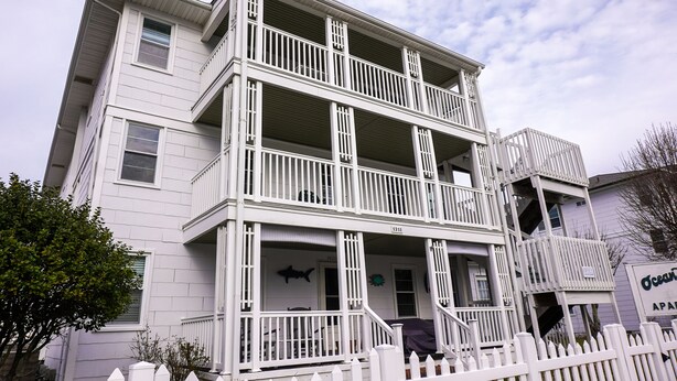 A multi-story building with a white exterior, balconies, and a sign indicating it is an apartment complex. - Ocean Terrace Family Apartments (Ocean City)