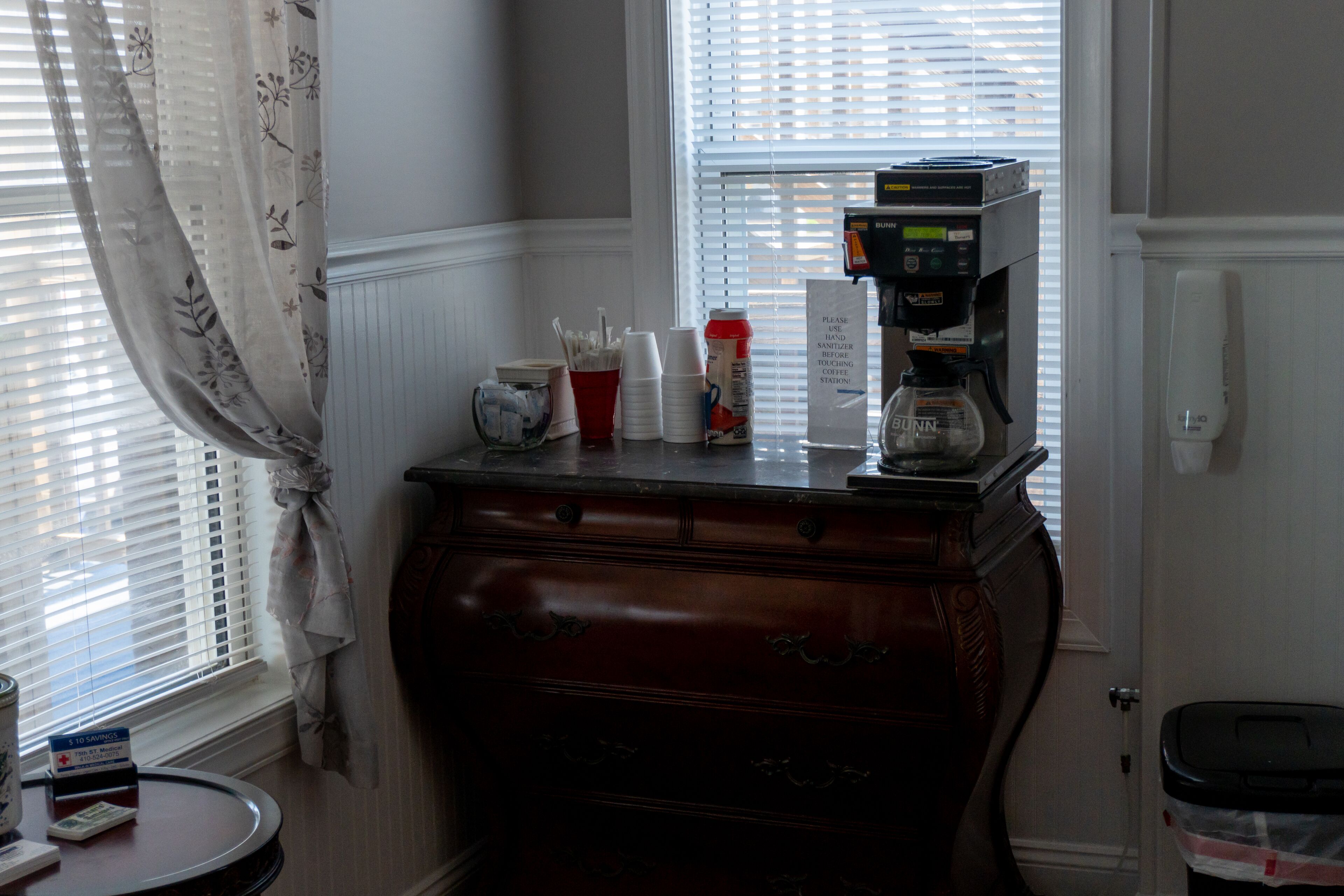 A coffee station with a coffee machine, cups, and condiments.