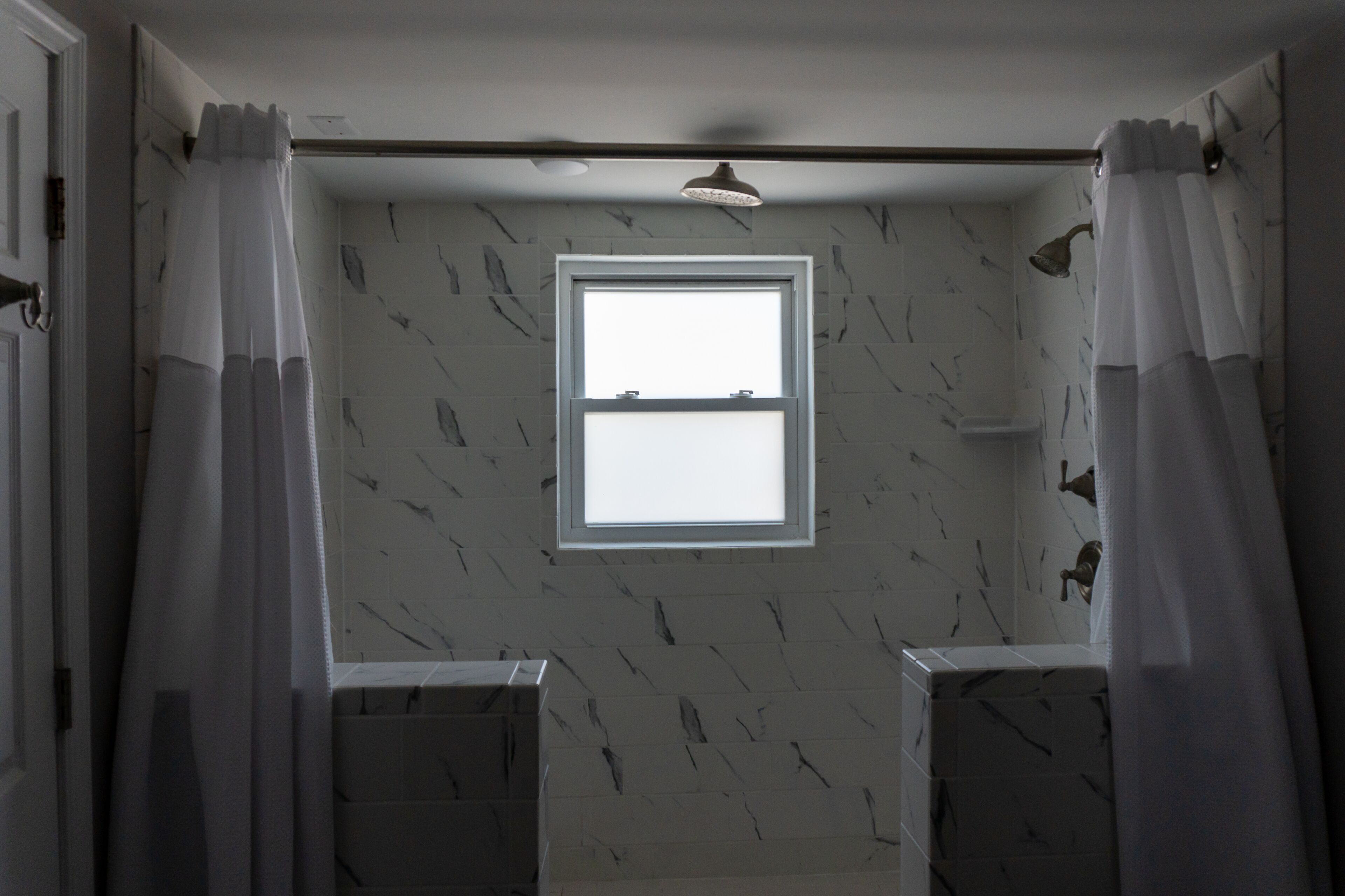 A bathroom with a window, two sinks, and a shower area.