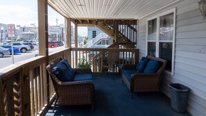 A covered porch with wicker furniture and a view of the street.