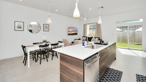 A modern kitchen with a central island, white cabinetry, and pendant lighting. - Modern Townhome-5 minutes to Downtown-Sleeps 9 Comfortably-King Suite (Houston)