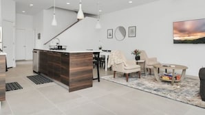 A modern kitchen with a central island, recessed lighting, and a dining area with a sofa and coffee table. - Modern Townhome-5 minutes to Downtown-Sleeps 9 Comfortably-King Suite (Houston)