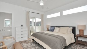A bedroom with a bed, a dresser, a nightstand, a lamp, a ceiling fan, and a window. - Modern Townhome-5 minutes to Downtown-Sleeps 9 Comfortably-King Suite (Houston)