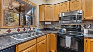 A kitchen with wooden cabinets, a stainless steel sink, a microwave, and a stove. - Contemporary Country Club Condo with portable A/C's in the bedrooms. (Flagstaff)