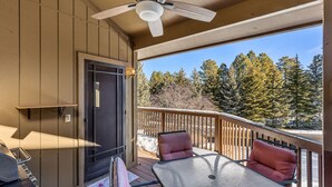 A covered outdoor area with a table and chairs, a ceiling fan, and a view of trees and a body of water. - Contemporary Country Club Condo with portable A/C's in the bedrooms. (Flagstaff)