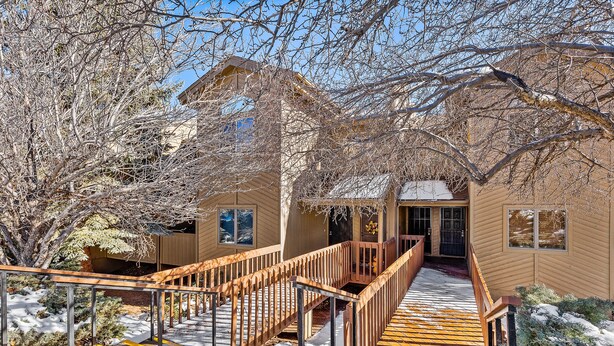 A wooden staircase leading to a building with a beige exterior and a covered entrance. - Contemporary Country Club Condo with portable A/C's in the bedrooms. (Flagstaff)