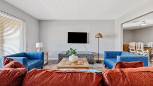 Ein Wohnzimmer mit zwei blauen Sofas, einem Holztisch mit einer Vase und einem roten Teppich.
