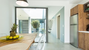 A modern kitchen with a wooden dining table, a stainless steel refrigerator, and a view into the dining area. - Captivating Panoramic Sea View, Unique Architecture, 10 Minutes from Beach




 (Σκουλούφια)