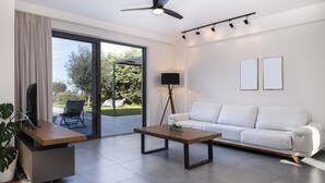 A modern living room with a white sofa, a wooden coffee table, a TV on a stand, a floor lamp, and a ceiling fan. - Captivating Panoramic Sea View, Unique Architecture, 10 Minutes from Beach




 (Σκουλούφια)