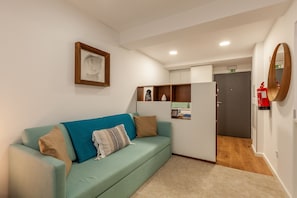 Una sala de estar moderna con un sofá color turquesa, un cuadro enmarcado y un espejo con marco de madera.