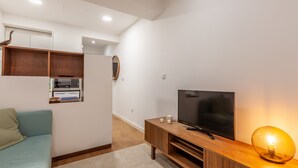 A modern living room with a sofa, wooden entertainment unit, TV, and a unique spherical lamp. - Underground Batalha Studios - B (Oporto)