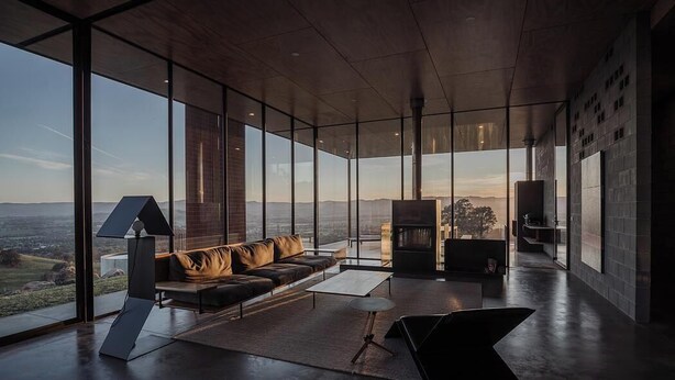 Een moderne woonkamer met een groot raam, een bank, een salontafel en een open haard.