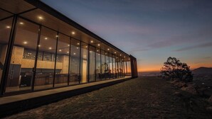 Een modern gebouw met grote glasramen, een plat dak en uitzicht op het landschap.