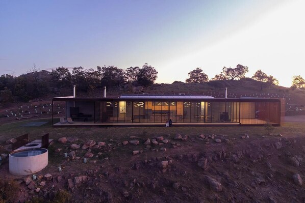 A modern building with large glass windows, a flat roof, and a seating area with chairs and tables. - Mansfield House (Mansfield)