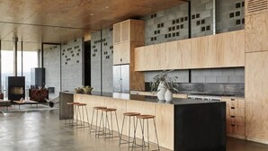 Een moderne keuken met een centraal eiland, barkrukken en een groot raam met uitzicht op de stadslijn.