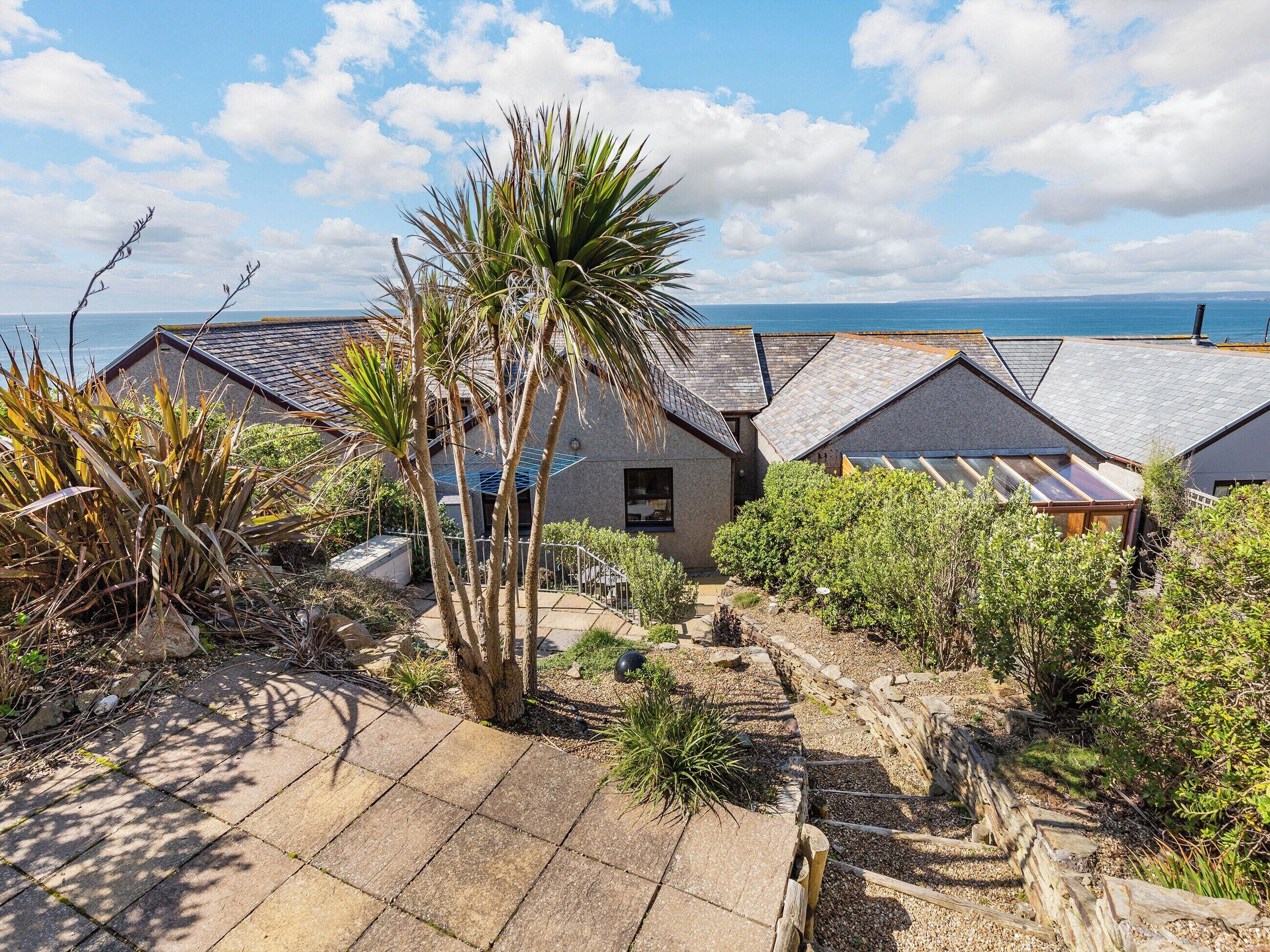 Una propiedad costera con varias casas, un patio empedrado y vistas al mar.