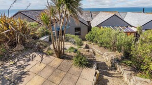 A coastal property with multiple houses, a paved patio, and a view of the sea. - 3 bedroom accommodation in Porthleven (Porthleven)