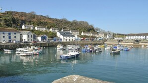 A harbor with boats docked, a stone quay, and buildings along the shore. - 3 bedroom accommodation in Porthleven (Porthleven)