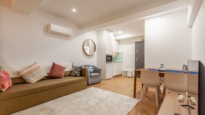A modern living room with a sofa, a coffee table, and a dining area with chairs and a table. - Underground Batalha Studios - D (Oporto)