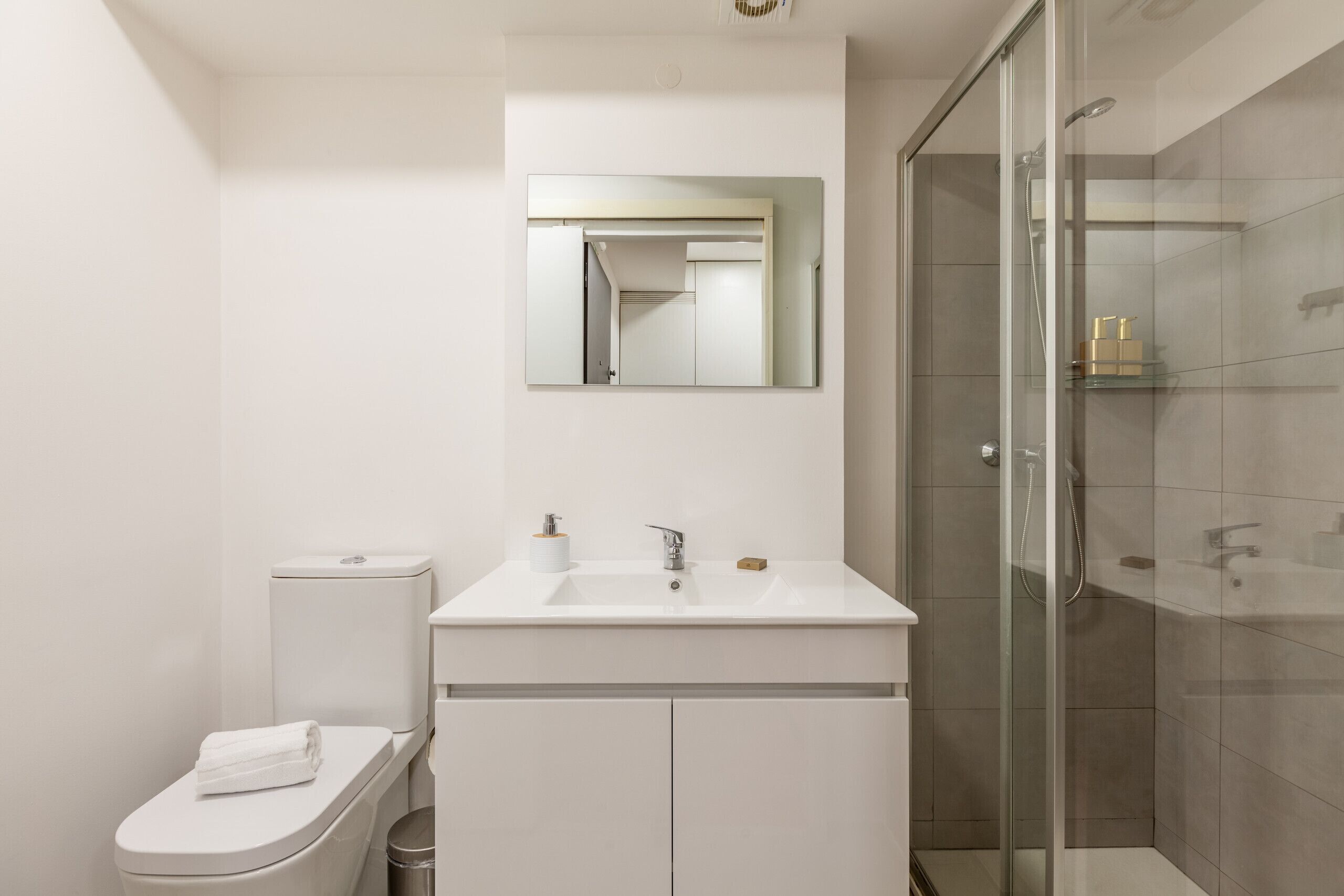 Een moderne badkamer met toilet, wastafel en douchecabine met glazen wanden.