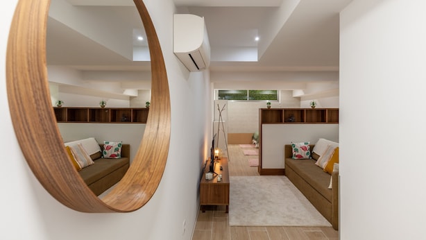 A modern living room with a large wooden mirror, built-in shelves, a sofa, and a small table with decorative items. - Underground Batalha Studios - E (Oporto)