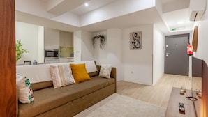 A modern living room with a sofa, a coffee table, and a kitchen in the background. - Underground Batalha Studios - E (Oporto)