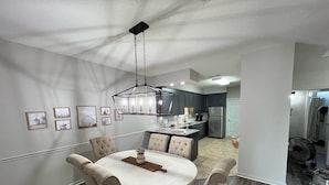 Una cucina moderna con mobili scuri, un frigorifero in acciaio inossidabile e un'area pranzo con un tavolo rotondo e quattro sedie.