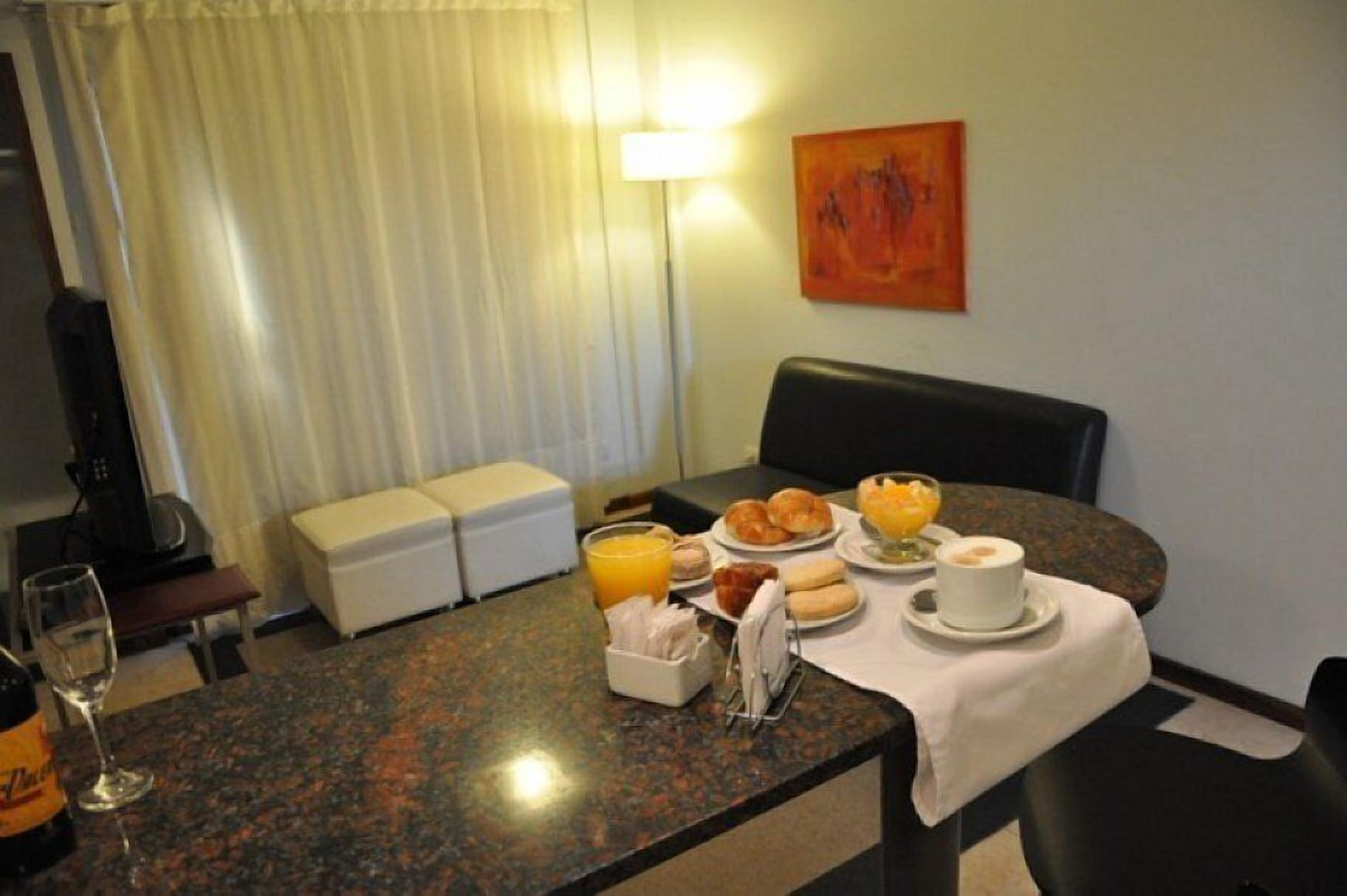Ein Hotelzimmer mit Frühstückstisch, einer Kaffeemaschine, einem Fernseher und einem Bild an der Wand.