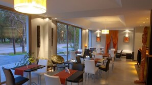 A modern dining area with tables and chairs, large windows, and decorative elements.