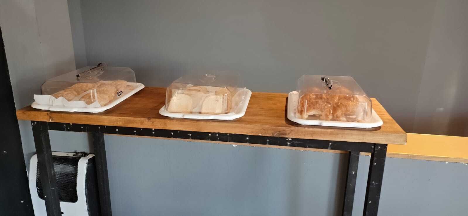 Three plastic-wrapped items on a wooden table against a grey wall.