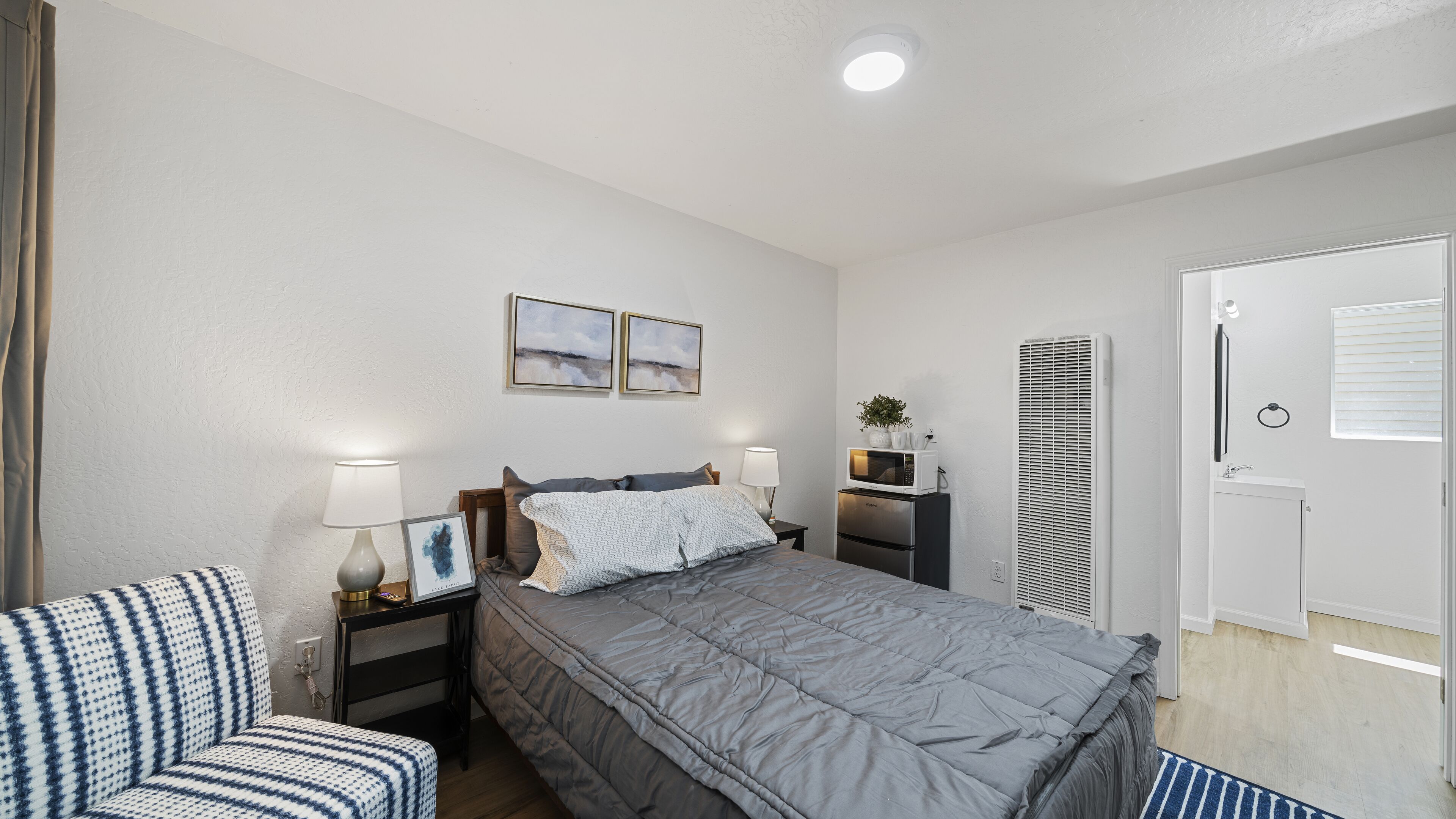 Quarto bem arrumado com cama, mesas de cabeceira, micro-ondas e um pequeno armário.