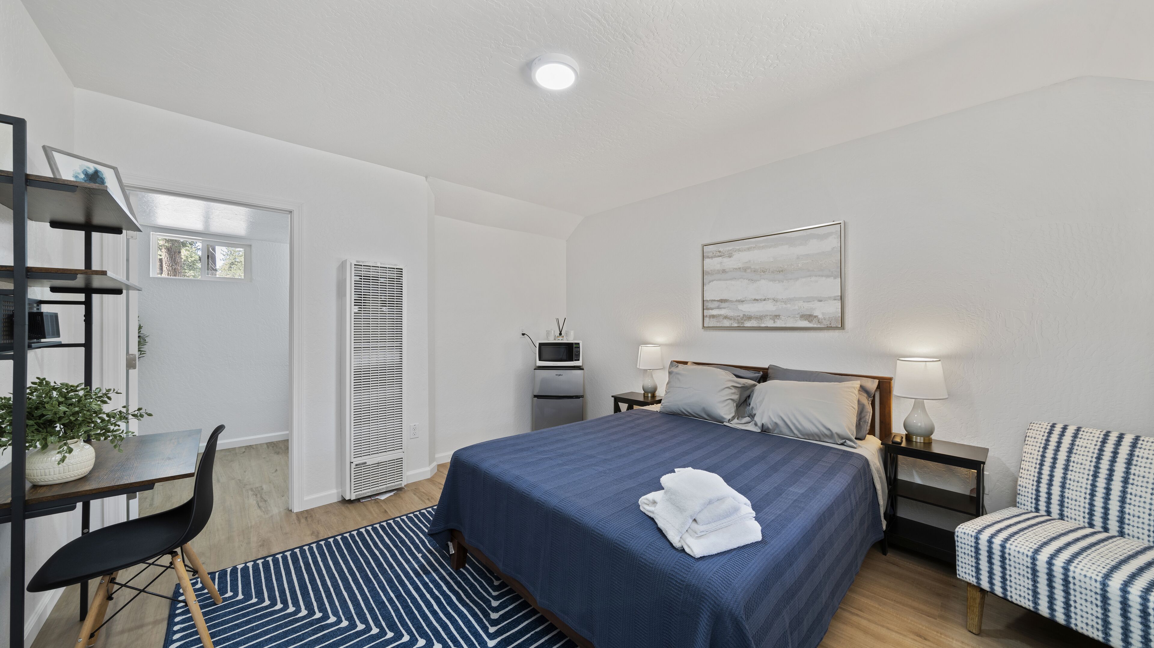 A modern bedroom with a bed, bedside tables, a desk, and a chair.