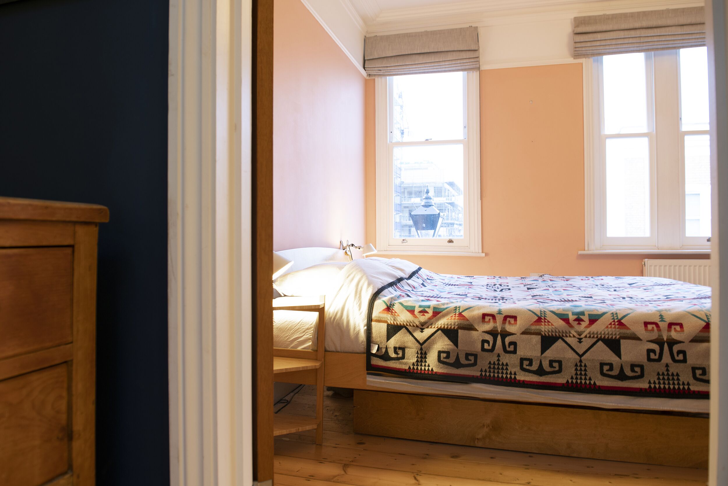 A bedroom with a bed, a wooden chair, and a window with blinds.