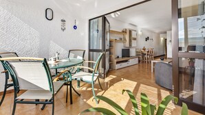 Un espacio habitable moderno con comedor, cocina y puerta de cristal que da a un área exterior.