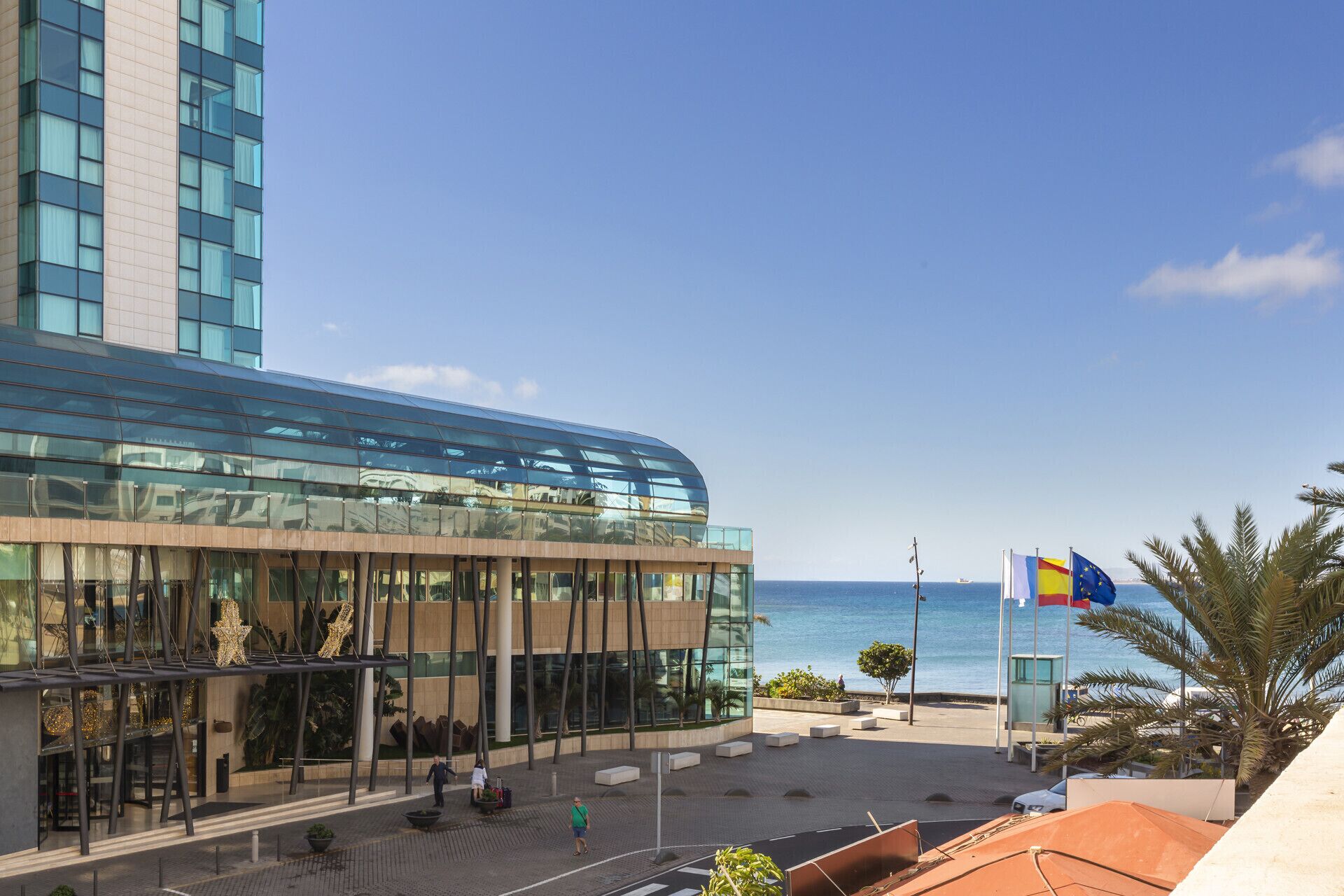 A modern building with a glass facade and a view of the sea.